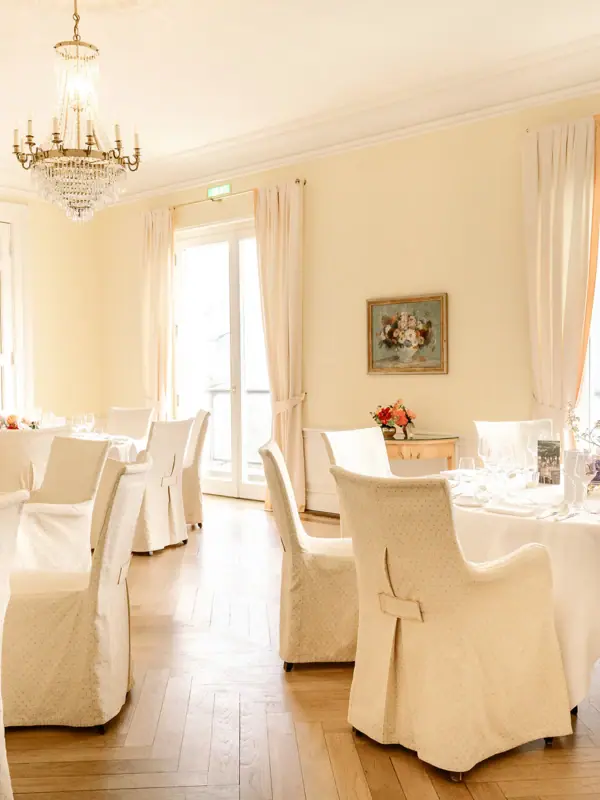 LCJ Hochzeitslocation Ein Raum mit Tischen und Stühlen, elegant eingerichtet mit Tischdecken und Vorhängen.