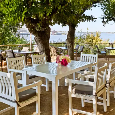 Liebermann-Tisch Weiße Tischgruppe unter Bäumen auf der Lindenterrasse.