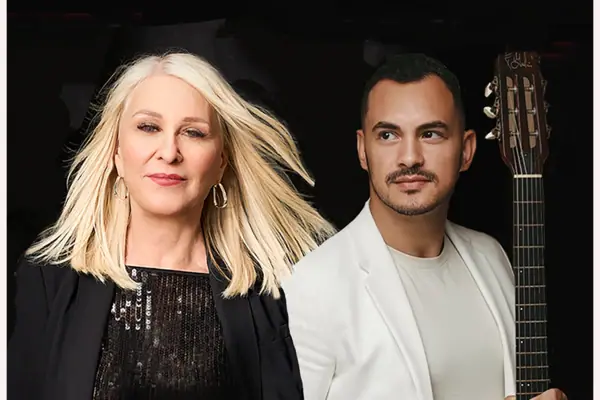 Ines Omenzetter & Santiago Ferreiro Ein Mann und eine Frau posieren lächelnd für ein Foto mit einer Gitarre.