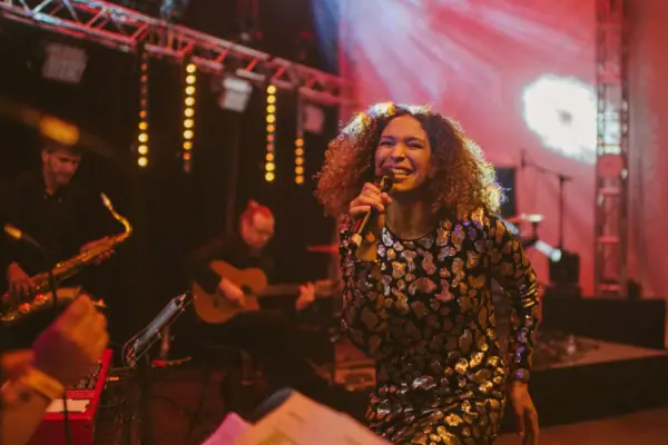 Nite Club Duo Eine Frau singt auf einer Bühne in ein Mikrofon.