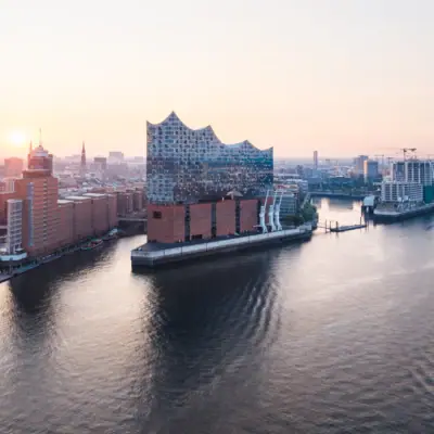 Elbphilharmonie Stadt mit Fluss und Gebäuden, im Vordergrund ein Schiff auf dem Wasser.