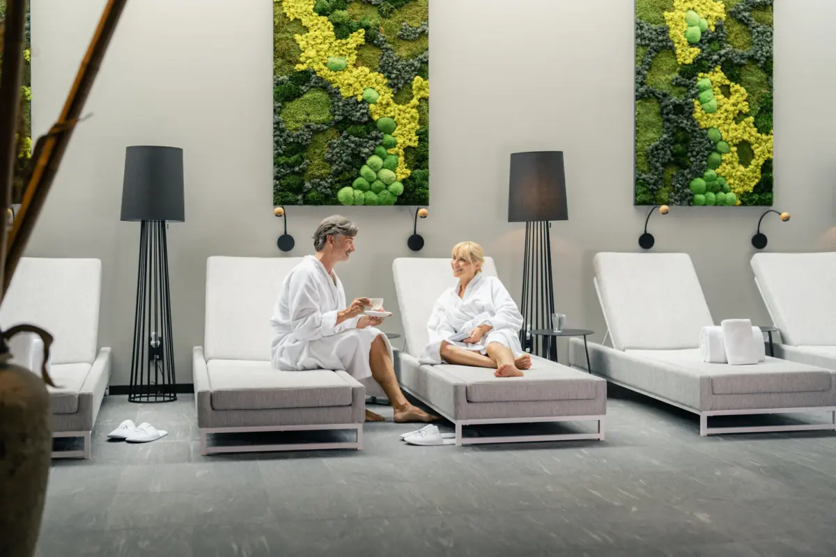 Wellnessbereich Ein Mann und eine Frau in weißen Bademänteln sitzen auf Entspannungsliegen im Wellness-Bereich des Hotels Louis C. Jacob..