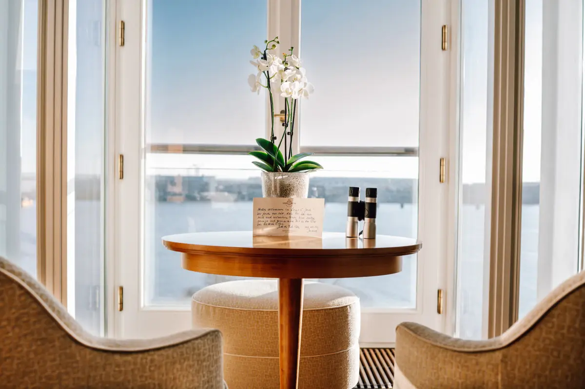 Ausblick Zimmer Ein Tisch mit einer Orchidee und einem Fernglas darauf mit der Elbe im Hintergrund