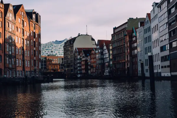 Häuserfassaden der Speicherstadt Hamburg an einem Kanal. Im Hintergrund ist die Elbphilharmonie zu erkennen.