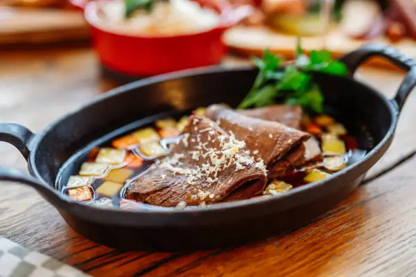 Gekochter Rindertafelspitz Eine gusseiserne Pfanne mit gekochtem Rindertafelspitz.