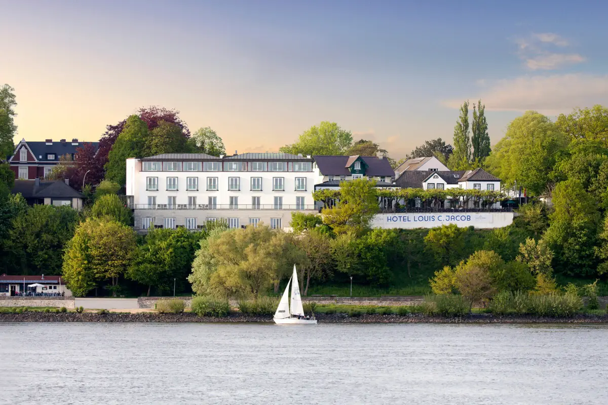 Außenansicht Louis C. Jacob Das Hotel Louis C. Jacob von der Elbe aus betrachtet mit einem Segelboot in Front.