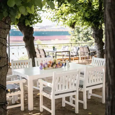 Liebermann-Tisch Weiße Tischgruppe unter Bäumen auf der Lindenterrasse.