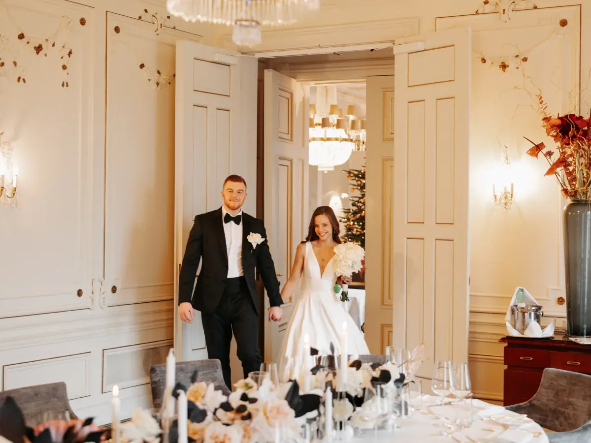 Hochzeitspaar frontal Ein Hochzeitspaar stehet neben einem Tisch mit Blumen.