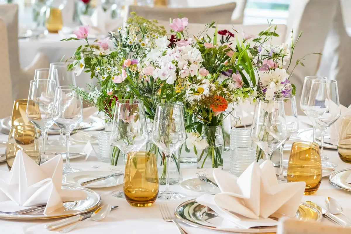 Feiern im Louis C. Jacob Ein festlich geschmückter Tisch mit Blumenarrangement und Weingläsern.