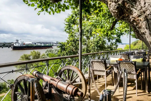 Lindenterrasse Lindenterrasse des Hotels Louis C. Jacob mit Gartenstühlen und Tischen sowie einer kleinen Kanone. Von der Reling kann man die Elbe und ein Containerschiff sehen.