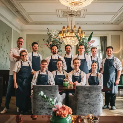 Jacobs Restaurant Team Team steht vor Kronleuchter und lächelt in die Kamera