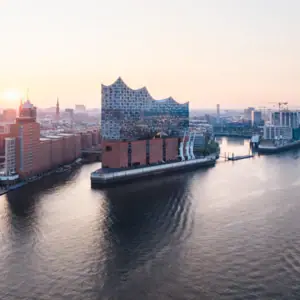 Elbphilharmonie Stadt mit Fluss und Gebäuden, im Vordergrund ein Schiff auf dem Wasser.