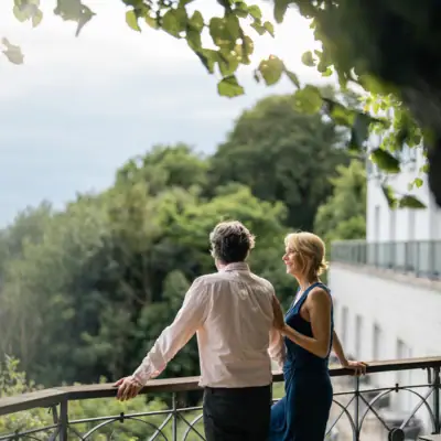 Sommer-Events auf der Lindenterrasse Ein Mann und eine Frau stehen nebeneinander an der Reling der Lindenterrasse des Hotels Louis C. Jacob und schauen auf die Elbe.