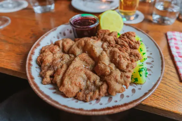 Original Wiener Schnitzel Ein Teller mit Wiener Kalbsschnitzel und Preiselbeeren.