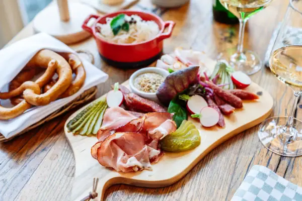 Schmankerl Brett Holzbrett mit typisch österreichischer Brotzeit aus Wurst, Schinken und Gemüse.