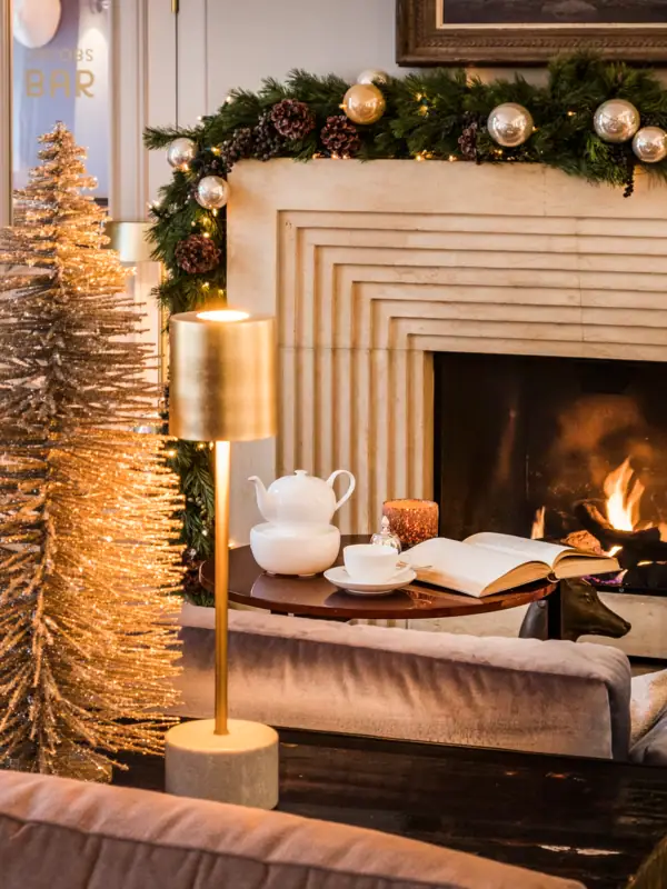 Sofa und Tisch vor dem Kamin in der weihnachtlich geschmückten Wohnhalle des Hotels Louis C. Jacob.