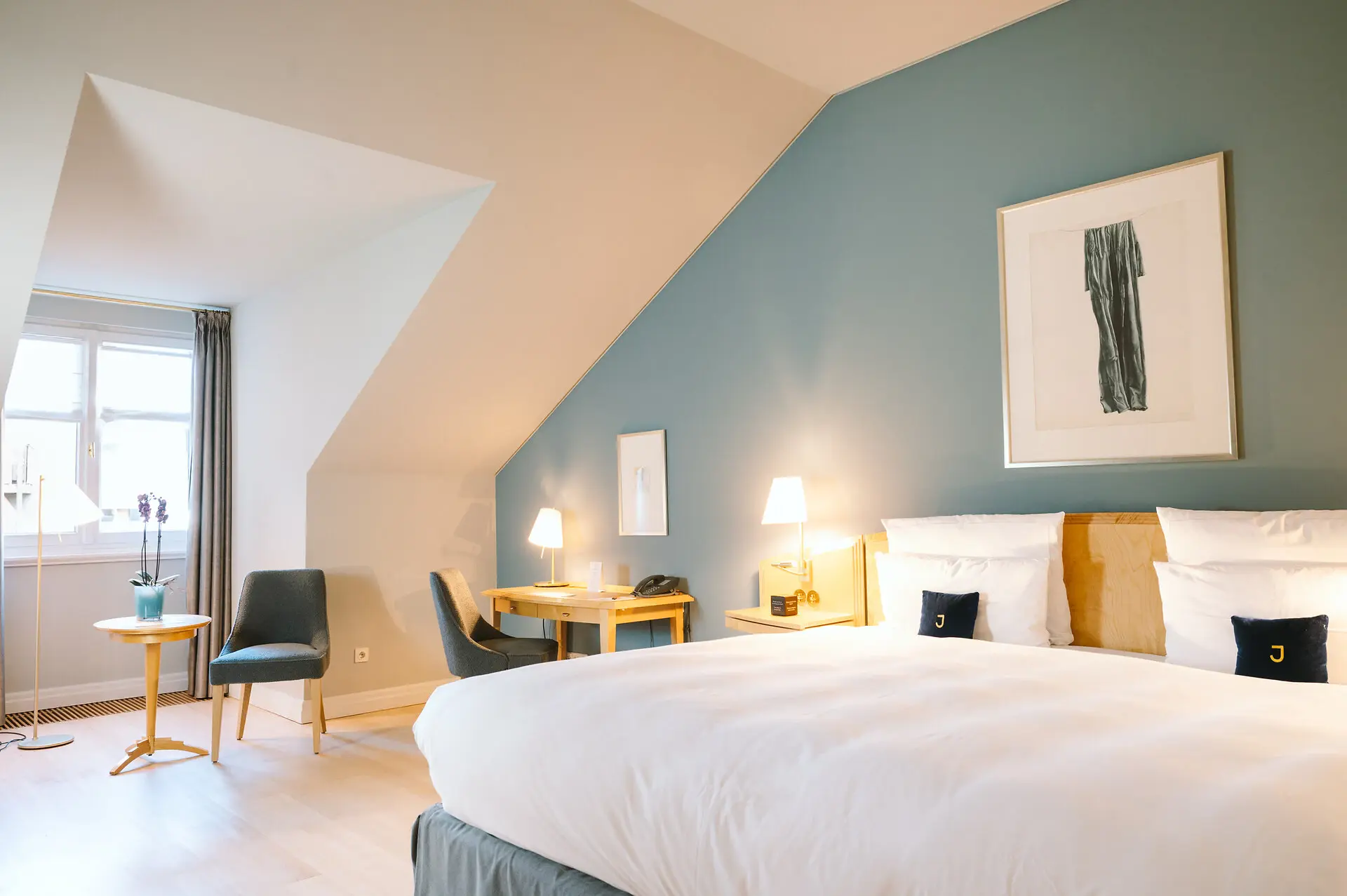 Doppelzimmer Louis C. Jacob Hotel Hamburg Hotelzimmer im Louis C. Jacob Hotel Hamburg mit einem Bett und einem Stuhl vor einer hellblauen Wand.