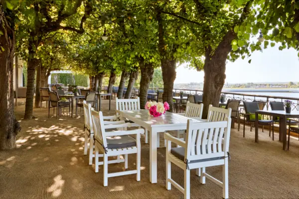 Lindenterrasse Hamburg Die Lindenterrasse in Hamburg mit Tischen und Stühlen unter Bäumen mit Blick auf die Elbe.