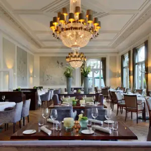 Gastronomie Ein Raum mit Tischen, Stühlen und Kronleuchtern.