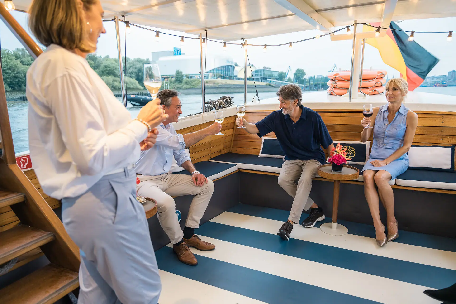 Mehrere Personen sitzen und stehen im überdachten Außenbereich der Barkasse MS Jacob.