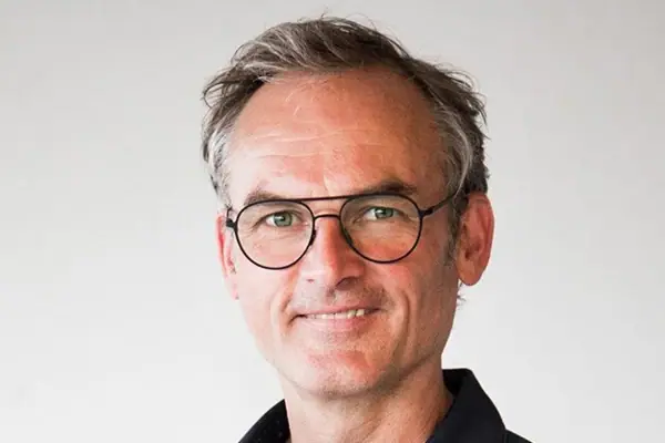 Sven Grot Ein Mann mit Brille und blauem Hemd lächelt.