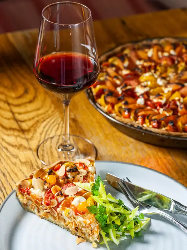 Ein Glas Wein neben einem Teller mit Essen.