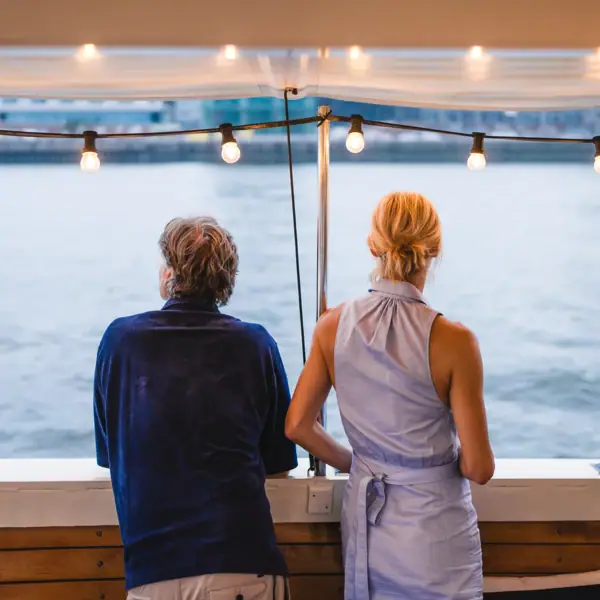 Ein Mann und eine Frau stehen an der Relig der barkasse MS Jacob und schauen aufs Wasser.