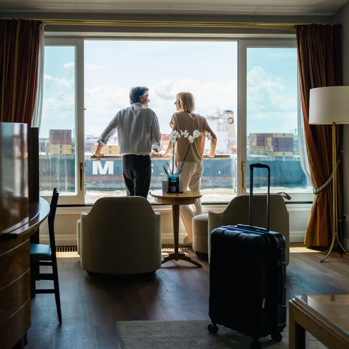 Zimmer Louis C. Jacob Hotel Hamburg Ein Mann und eine Frau stehen in einem mit Hotelzimmer an einem Fenster und schauen auf die Elbe.