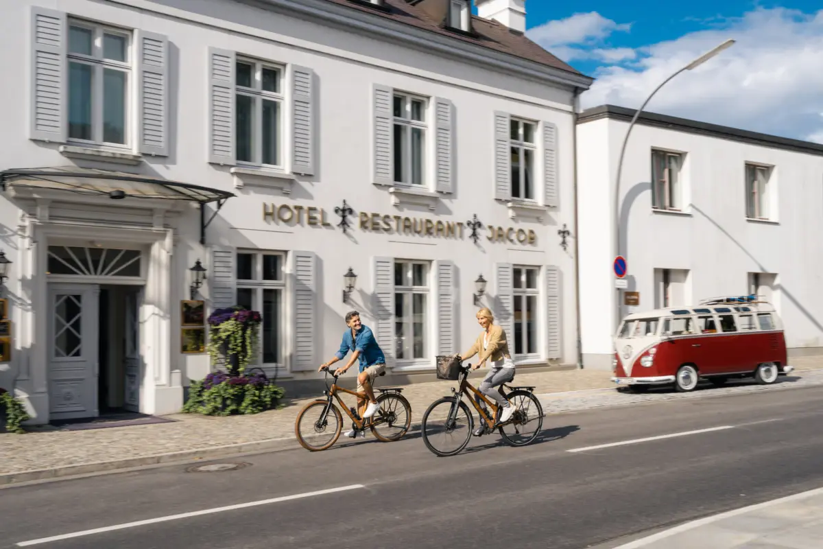 Außenansicht Louis C. Jacob Ein Mann und eine Frau fahren Fahrrad auf der Straße vor dem Eingang zum Hotel Louis C. Jacob.