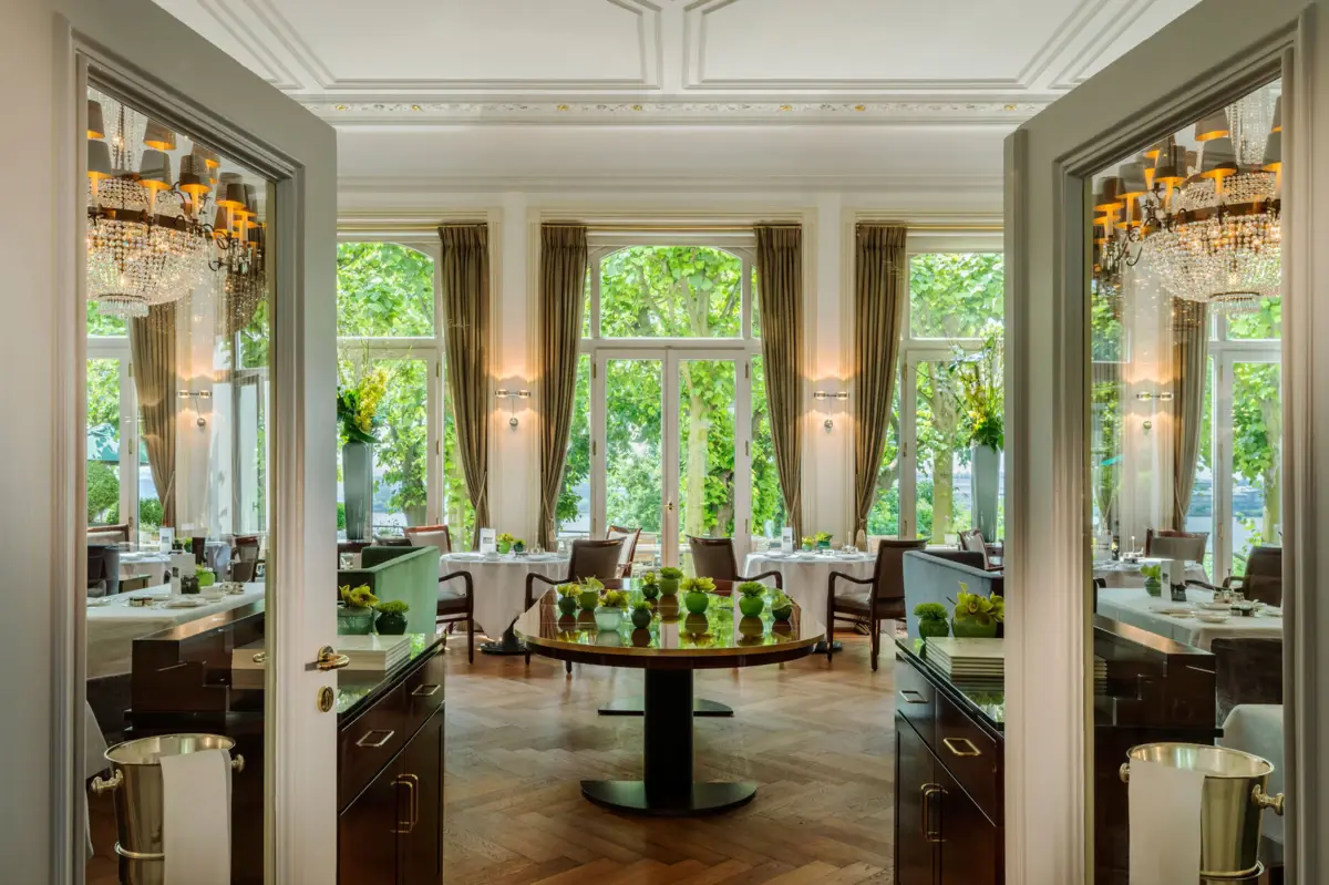Jacobs Restaurant Hamburg Das Jacobs Restaurant mit Tischen, Stühlen und hohen Fenstern sowie Kronleuchtern.