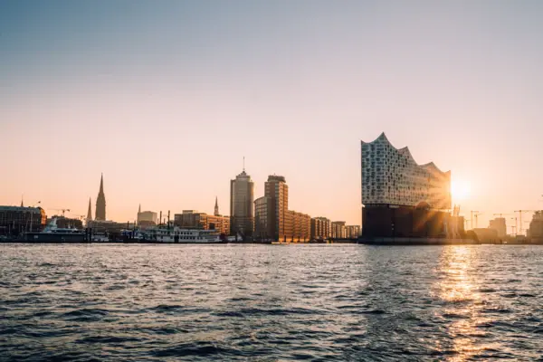 Blick von der Elbe aus auf den Hafen Hamburg und die Elbphilharmonie bei Sonnenuntergang.