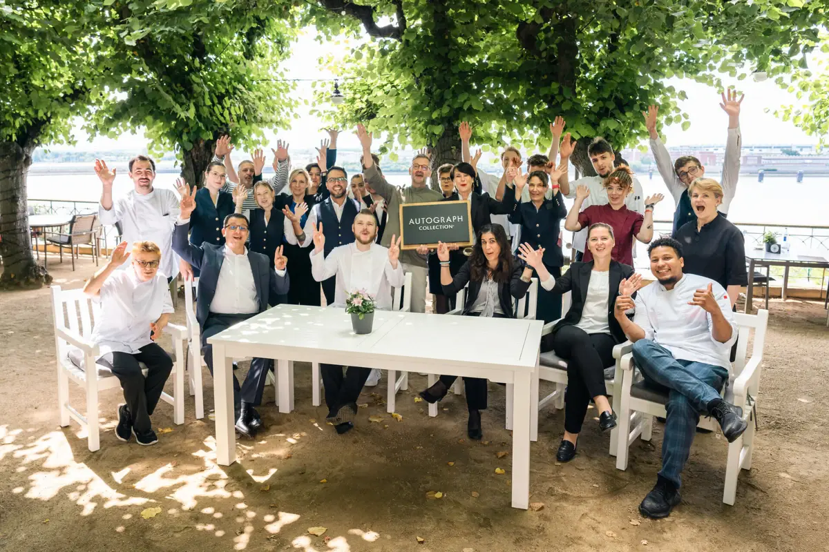 Team Louis c. Jacob Das Hotel- und Service-Team des Hotels Louis C. Jacob sitzt und steht versammelt auf der Lindenterrasse.