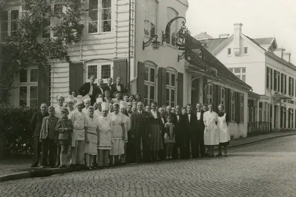 Louis C Jacob Eine Gruppe von Menschen steht vor einem Gebäude.