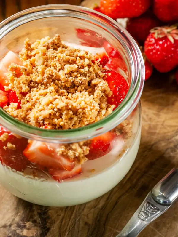 Nachspeise Ein Glas Dessert mit Erdbeeren und einem Löffel.