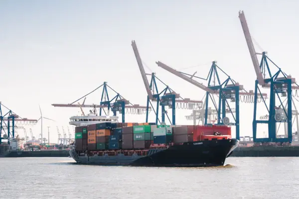 Blick auf die Elbe, ein Containerschiff und den Containerhafen mit Kränen in Hamburg.