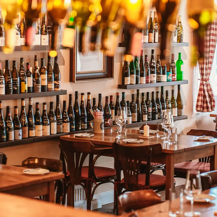 Ein Raum mit Tischen, Stühlen und Weinflaschen.